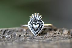 This listing is for one beautifully detailed sacred heart ring. The sacred heart featured intricate details of flames and hearts surrounding the center heart. It is fired onto sturdy 14 gauge sterling silver wire. Wear this ring solo for simple elegance of wear it stacked with several hammered bands for an edgier, bohemian style! - Choose your ring size and stacking options at checkout! - Sacred Heart measures 15 by 10mm. - Made to Order: please see current processing times in Shipping Info and Bohemian Heart-shaped Anniversary Rings, Symbolic Heart-shaped Wedding Ring, Symbolic Heart Shaped Wedding Rings, Symbolic Heart-shaped Promise Ring, Bohemian Heart-shaped Rings For Gifts, Adjustable Engraved Heart Ring, Burning Heart, Angel Ring, Flaming Heart