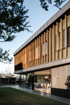 the outside of a modern building with wooden slats on it's side and grass in front