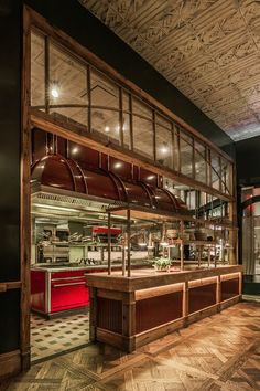 the interior of a restaurant with wood flooring and red oven hoods on display