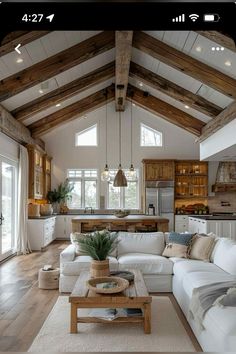 a living room filled with lots of furniture and wooden beams on the ceiling over a kitchen