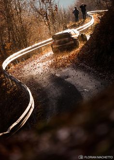 two people standing on the side of a road next to a car that is upside down