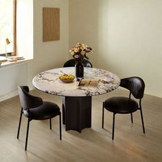 a dining room table with chairs and a vase filled with flowers on top of it