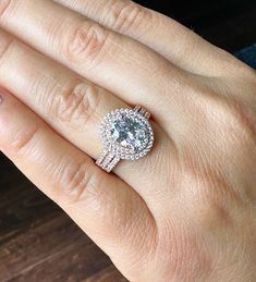 a woman's hand with a diamond ring on top of her finger and the other hand holding an engagement ring