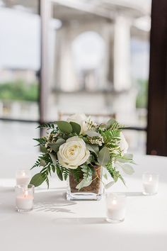 a vase filled with white flowers sitting on top of a table next to lit candles