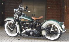 a green and white motorcycle parked in front of a brick building