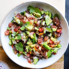 a white bowl filled with vegetables on top of a wooden cutting board next to a knife