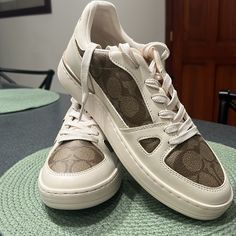 Brand New - Never Worn - Coach Clip Sig Court Lt Sneakers! These Sneakers Are Khaki/Chalk In Color With The Coach Insignia. These Are Beautiful Sneakers And Compliment Just About Any Outfit! I Just Don’t Need Them! Trendy Cream Sneakers With Perforated Toe Box, Trendy Flat Cream Sneakers, Trendy Cream Flat Sneakers, Trendy Cream Slip-on Sneakers, Beige Flat Sneakers With Perforated Toe Box, Trendy Coach Sneakers For Spring, Beige Flat Sneakers With Laces, Casual White Coach Sneakers, Coach Beige Sneakers With Round Toe