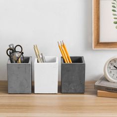 a desk with a clock, pen and pencil holder