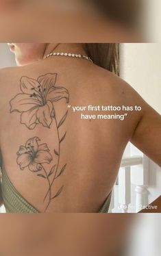 the back of a woman's shoulder with flowers on it and a quote about tattoos