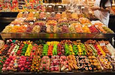 a woman is standing in front of a display of fruits and veggies at a market