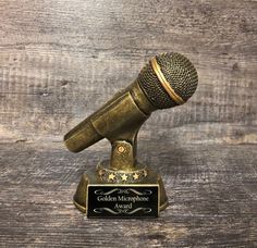 an old microphone on top of a wooden table next to a plaque that says golden microphone