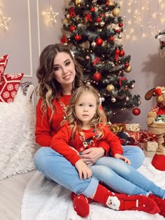 a woman and child sitting in front of a christmas tree