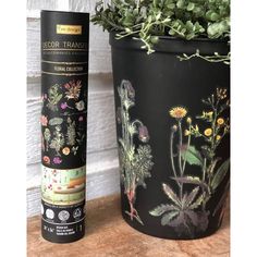 a black pot with flowers and plants painted on it next to a planter filled with succulents