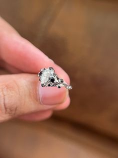 a person holding an engagement ring in their left hand, with the diamond on it's side