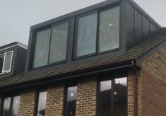 a brick building with three windows and a black roof