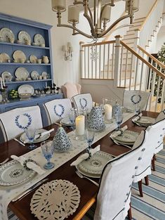 the dining room table is set with blue and white china, candles, and plates