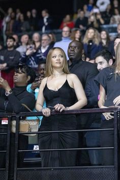 a woman in a black dress standing next to a crowd