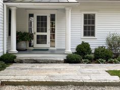 a white house with some plants on the front porch