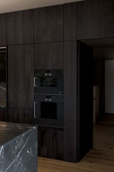 an empty kitchen with marble counter tops and black ovens in the wall behind it