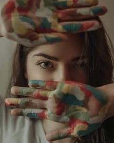 a woman with painted hands covering her face