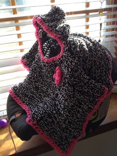 a crocheted black and pink hat sitting on top of a window sill