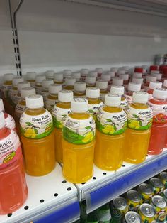 bottles of lemonade and orange juice are on display in a grocery store, along with other drinks