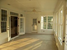 the sun shines through two windows in an empty room with white walls and doors