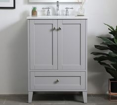 a bathroom vanity with two drawers and a mirror above it, next to a potted plant