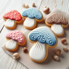 decorated cookies with different colors and designs on a white tablecloth next to nuts in the shape of mushrooms