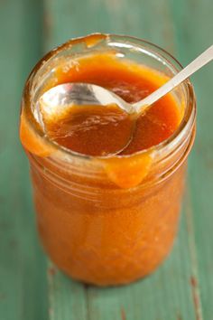 a spoon in a jar filled with orange sauce