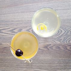 two glasses filled with drinks sitting on top of a wooden table