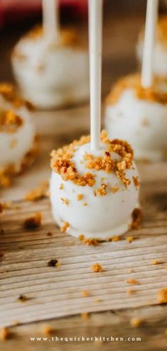 cake pops with white frosting and orange sprinkles on a wooden table