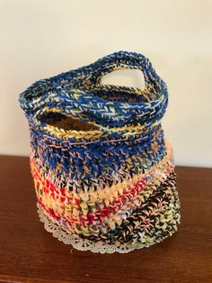 multicolored crocheted basket sitting on top of a wooden table