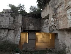 an old building that has been built into the side of a cliff with yellow light coming from it