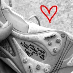 a pair of shoes with writing on them and a red heart in the back ground