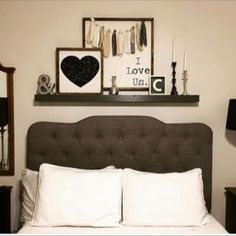 a bed with white sheets, pillows and pictures on the wall above it in a bedroom