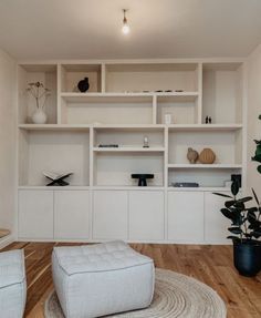 a living room filled with white furniture and lots of shelves on top of each other