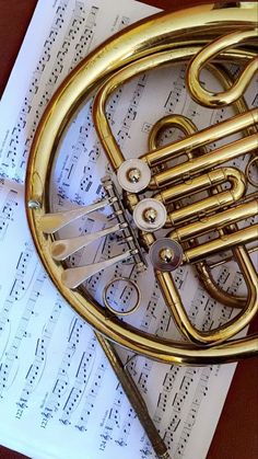 a brass french horn laying on top of sheet music