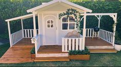 a small white house sitting on top of a wooden deck