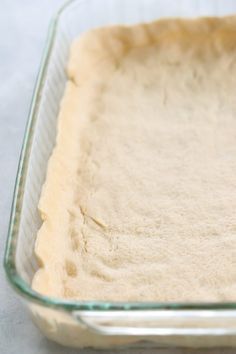 a glass baking dish filled with uncooked dough on top of a white table