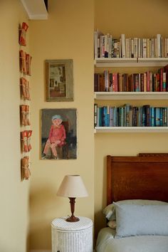 a bedroom with bookshelves and pictures on the wall above it, along with a bed