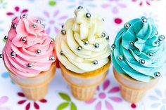 three ice cream cones with colorful frosting and studded decorations on top of them