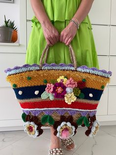 a woman is holding a multicolored purse with flowers on the front and sides