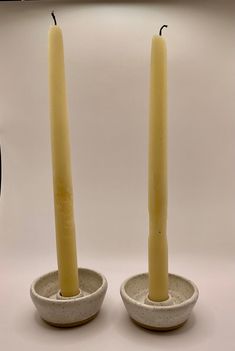 two candles are sitting in small bowls on a table