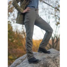 a woman standing on top of a rock with her hands on her hips and arms behind her back