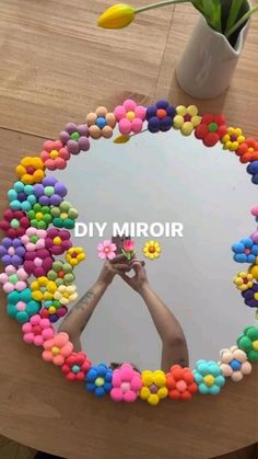 a hand holding a flower in front of a mirror with the words diy mirror on it