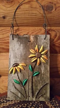 a wooden sign with two flowers painted on it's front and back sides, hanging from a rope