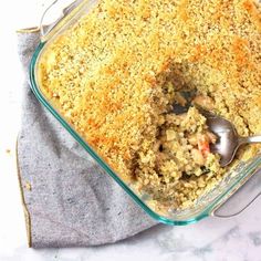 a glass casserole dish filled with meat and bread crumbs next to a silver spoon