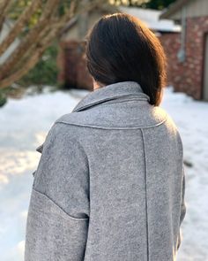 the back of a woman's head as she stands in front of a snow covered yard