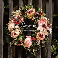 a wreath with flowers hanging on a fence